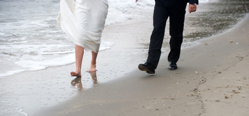 Bride and groom walk on the beach