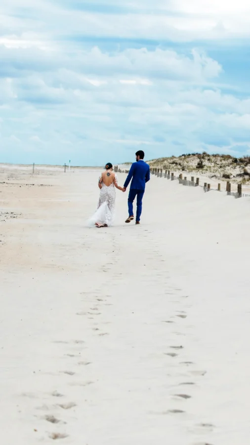 Wedding photography photos! A newly married couple walks behind a fence at a Beach in Maryland. JAX Photography 2023
